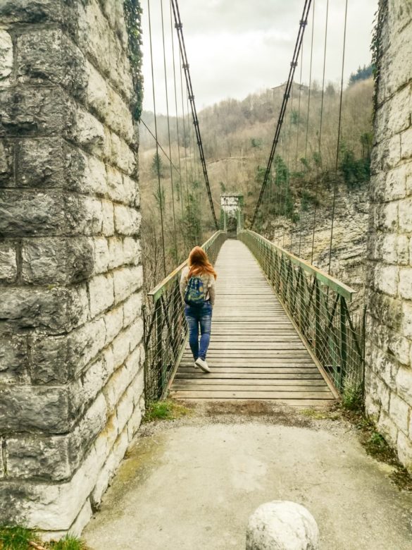una ragazza bionda, con dei jeans e uno zainetto lungo il ponte di Arsiè