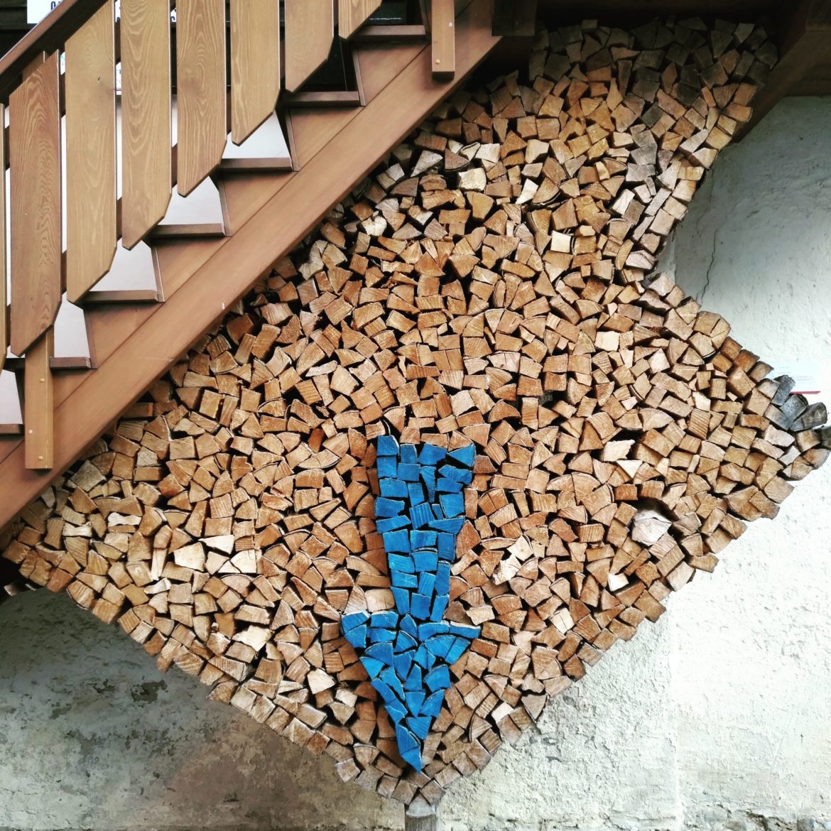 Catasta di legna con freccia colorata verso il basso.